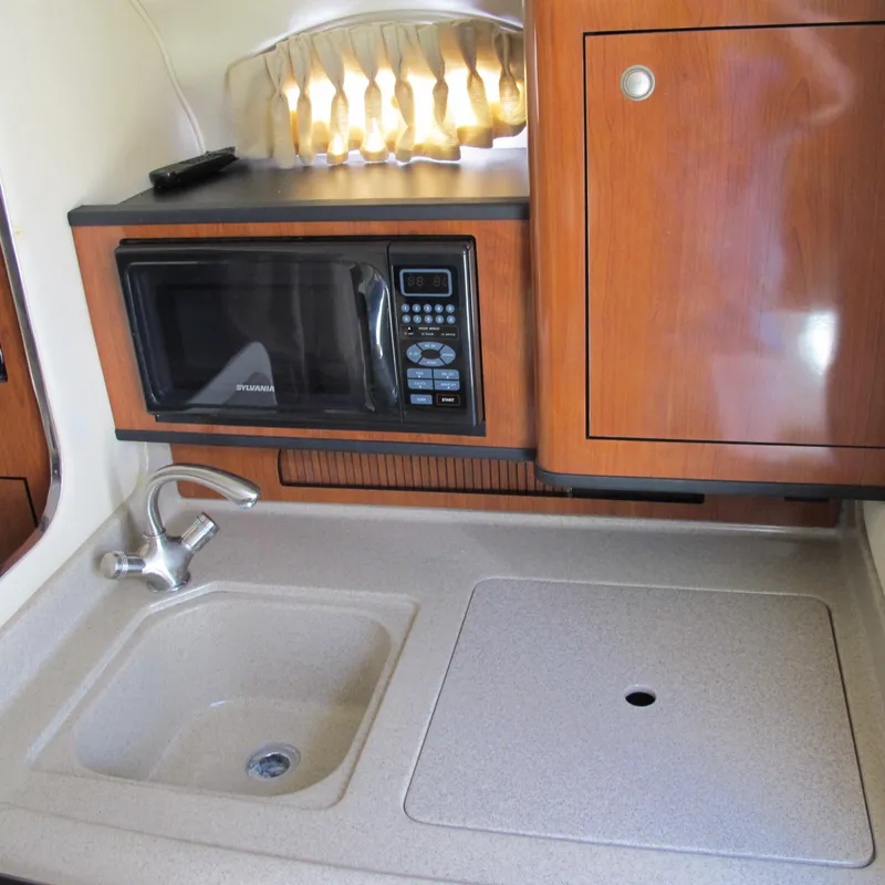 Slide: The Image of 2007 Sea Ray 280 DA galley with microwave, sink, and wooden cabinetry. - 23