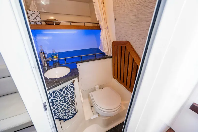 Slide: The Image of 2019 Boston Whaler 350 Realm bathroom with sink, toilet, and blue accent lighting. - 10