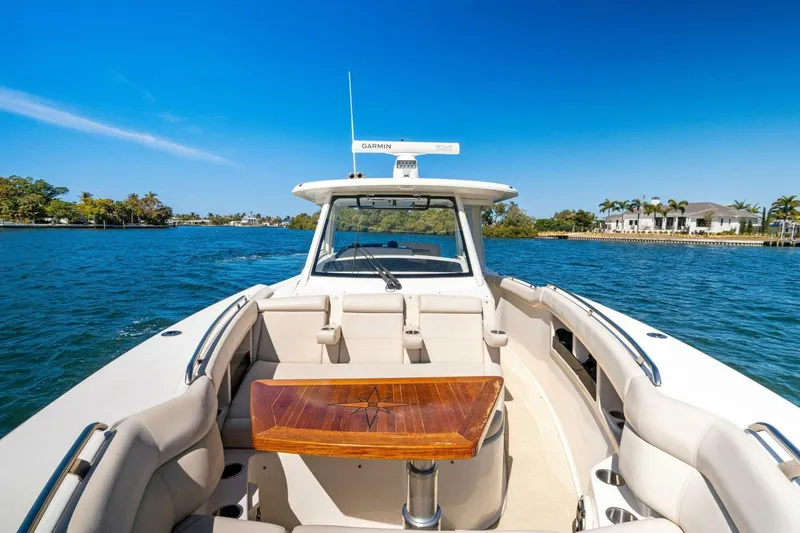 Slide: The Image of 2019 Boston Whaler 350 Realm boat on calm water, featuring spacious seating and a wooden table. - 13