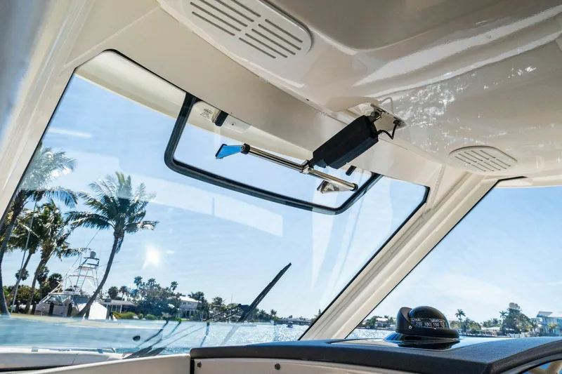 Slide: The Image of 2019 Boston Whaler 350 Realm interior view with windshield and ocean backdrop. - 18