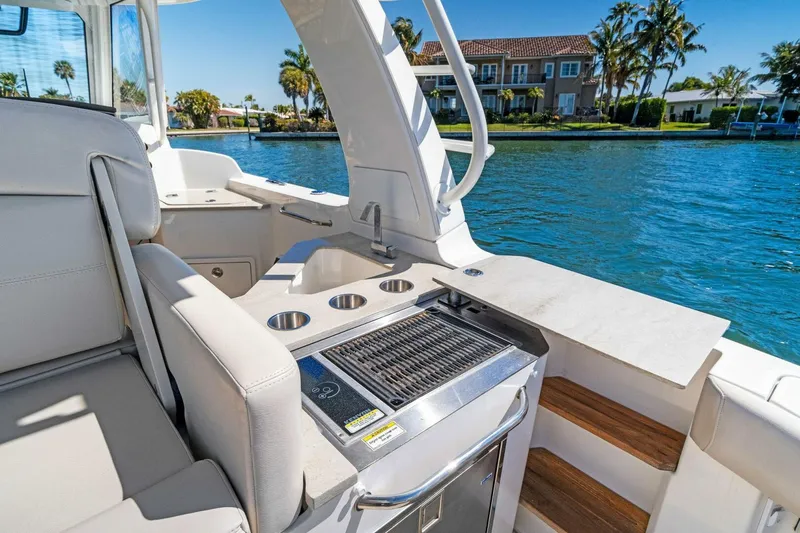 Slide: The Image of 2019 Boston Whaler 350 Realm boat interior with grill and seating by the water. - 24