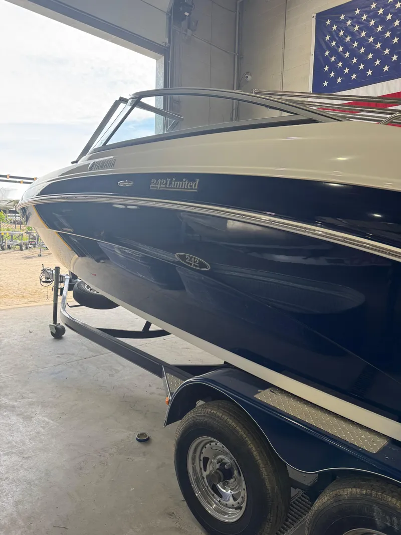 Slide: The Image of 2011 Yamaha Boats 242 Limited on trailer in garage, American flag in background. - 2