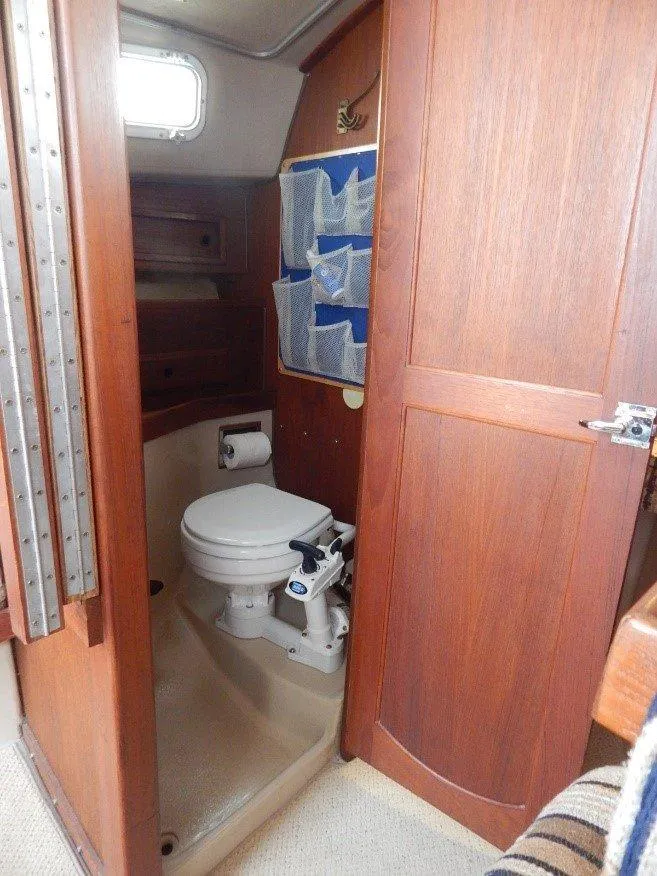 Slide: The Image of 1983 Newport 28 Sloop bathroom with wooden door and compact toilet. - 10