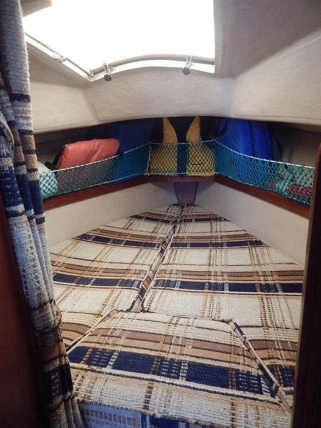 Slide: The Image of Cozy cabin interior of 1983 Newport 28 Sloop with plaid bedding and storage nets. - 12