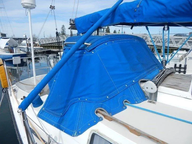 Slide: The Image of 1983 Newport 28 Sloop with blue canvas cover docked at marina. - 5