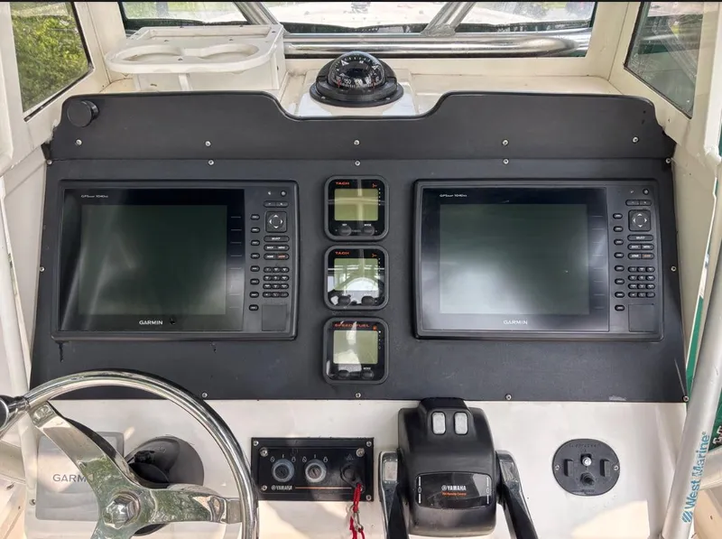 Slide: The Image of Boat dashboard with dual Garmin displays, steering wheel, and controls on a 1996 Mako 241 model. - 4