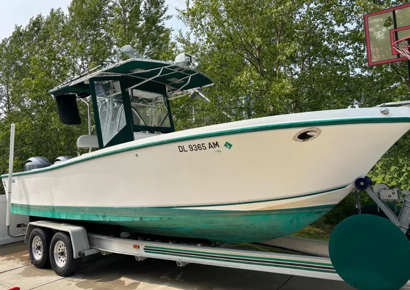 Slide: The Image of 1996 Mako 241 boat on trailer, white and green, parked outdoors near trees. - 5