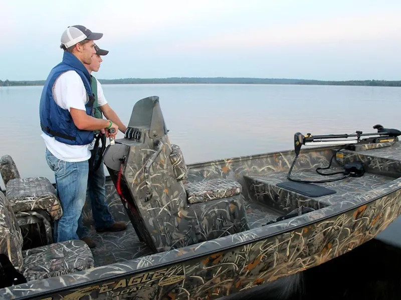 Slide: The Image of Two people on a 2026 War Eagle Blackhawk 961 boat on a calm lake. - 2