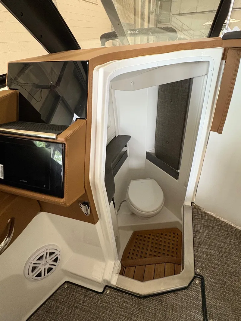 Slide: The Image of 2025 Cobalt R35 boat interior with compact bathroom, featuring a toilet and wooden flooring. - 7