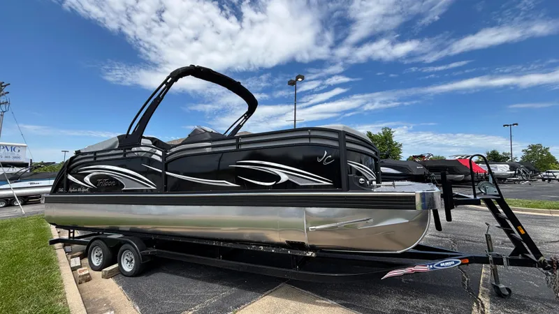 The Image of 2025 JC Neptoon 25TT Sport pontoon boat on trailer under blue sky. - 0