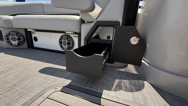 Slide: The Image of 2025 JC Neptoon 25TT Sport boat interior with open storage compartment and speaker system. - 32