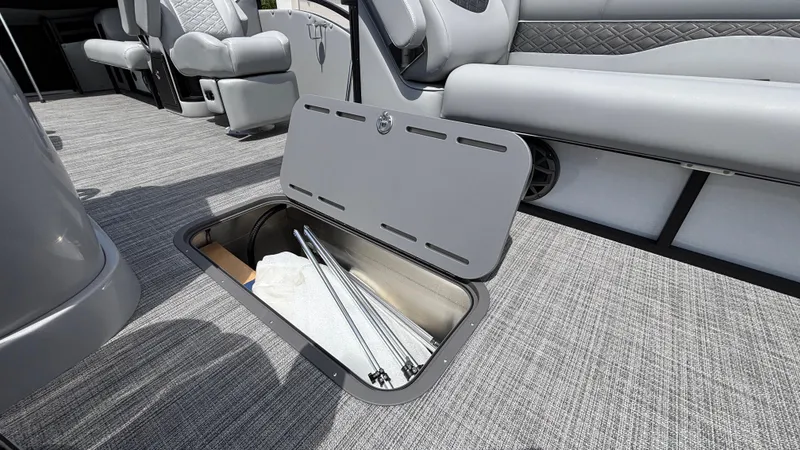 Slide: The Image of 2025 JC Neptoon 25TT Sport pontoon boat with open storage compartment and gray seating. - 5