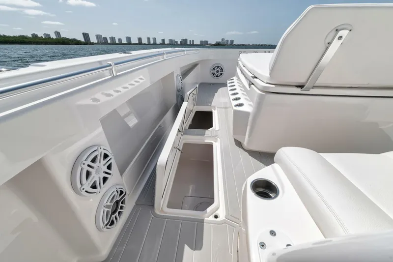 Slide: The Image of 2018 Invincible 40 Catamaran interior with seating, storage, and speakers on a sunny day. - 20