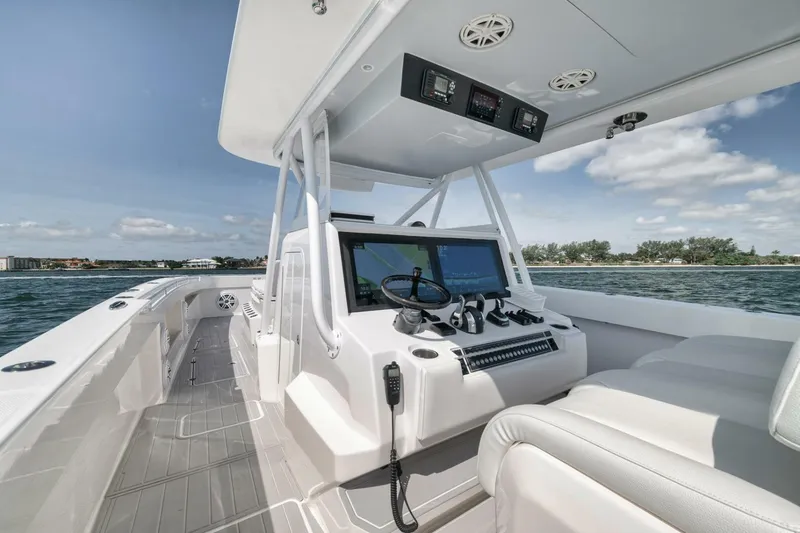 Slide: The Image of 2018 Invincible 40 Catamaran helm with dual screens, steering wheel, and ocean view. - 23