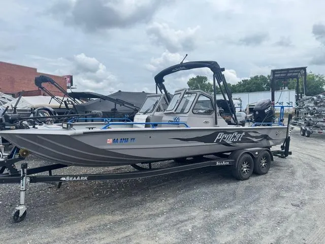 Slide: The Image of 2023 SeaArk Pro Cat 240 boat on trailer, parked outdoors under cloudy sky. - 1