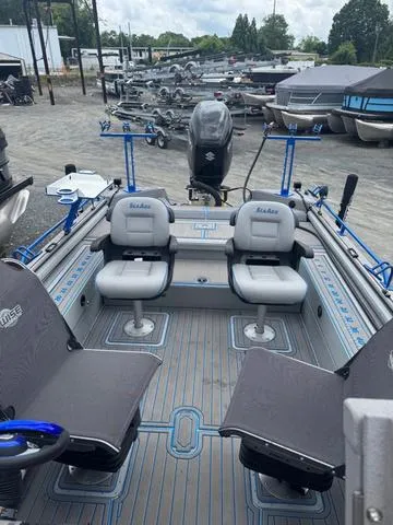 Slide: The Image of 2023 SeaArk Pro Cat 240 boat with seating and fishing setup, parked in a marina. - 14