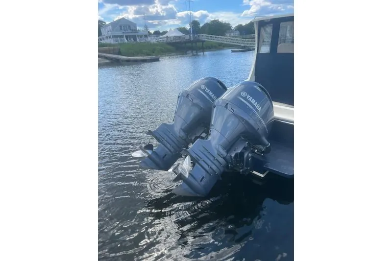 Slide: The Image of Twin Yamaha outboard motors on a 2016 Eastern 27 Islander boat, docked by a scenic waterfront. - 9