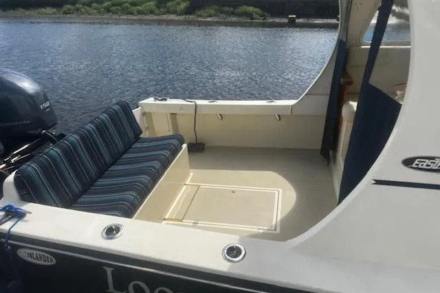 Slide: The Image of 2016 Eastern 27 Islander boat with striped seating, docked by a calm river. - 11