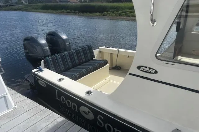 Slide: The Image of 2016 Eastern 27 Islander boat docked, featuring twin outboard motors and striped seating. - 7