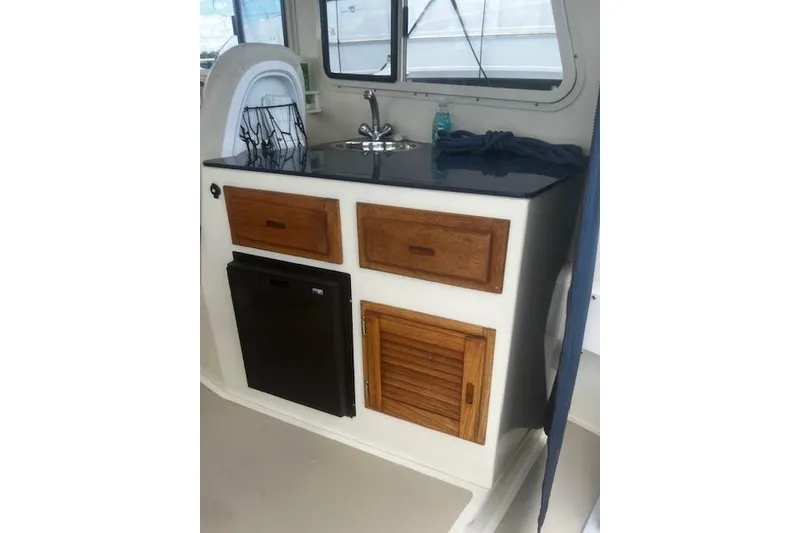 Slide: The Image of Compact galley area in 2016 Eastern 27 Islander boat with sink, storage, and mini fridge. - 15