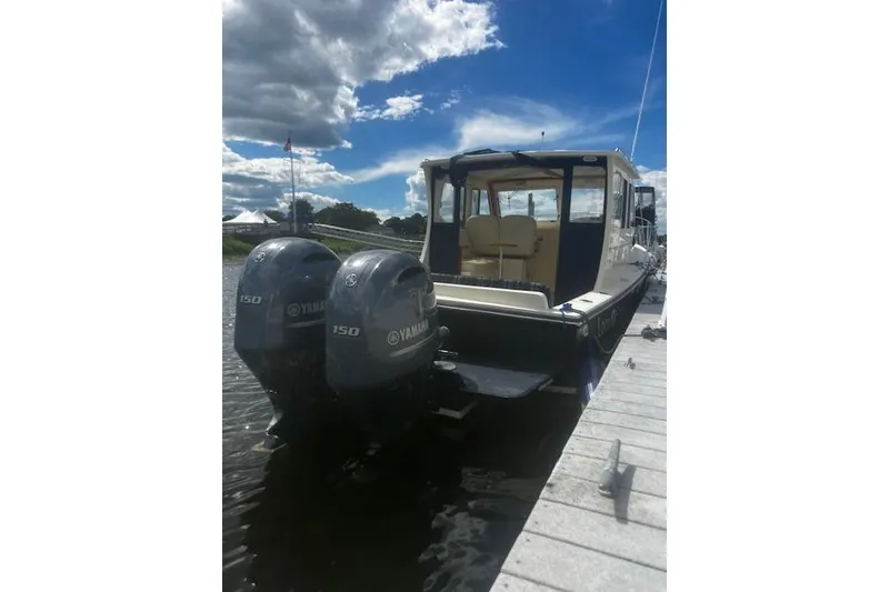 Slide: The Image of 2016 Eastern 27 Islander boat docked, featuring twin Yamaha 150 engines under a partly cloudy sky. - 6