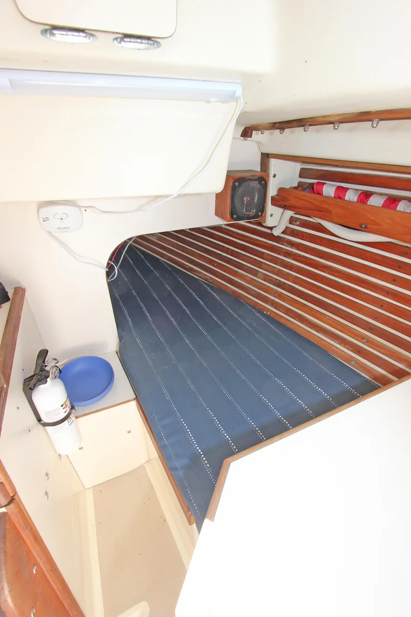 Slide: The Image of 1977 Pearson 10M sailboat interior with cozy sleeping berth and wooden accents. - 10