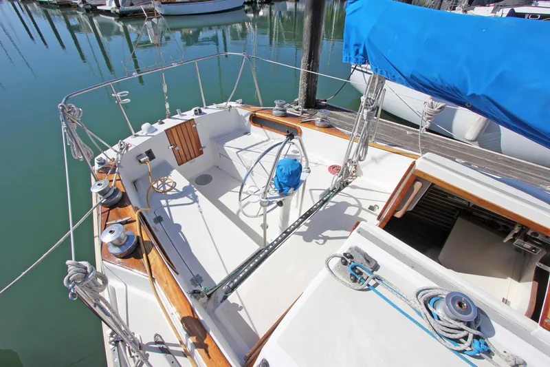 Slide: The Image of 1977 Pearson 10M sailboat cockpit with blue cover, docked in marina. - 13