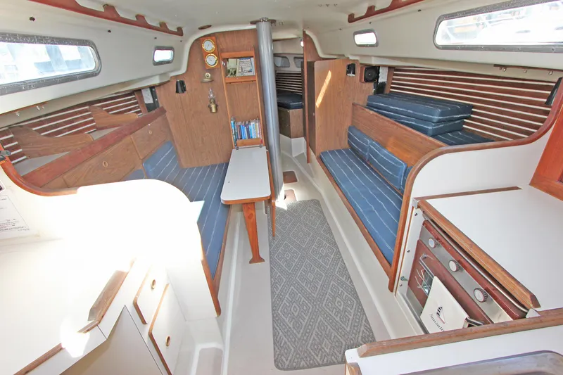 Slide: The Image of Interior of a 1977 Pearson 10M sailboat with wood paneling and blue seating. - 3