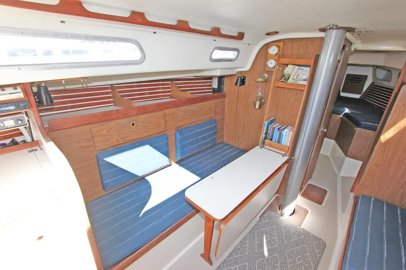 Slide: The Image of 1977 Pearson 10M sailboat interior with blue seating, wooden accents, and a compact table. - 5