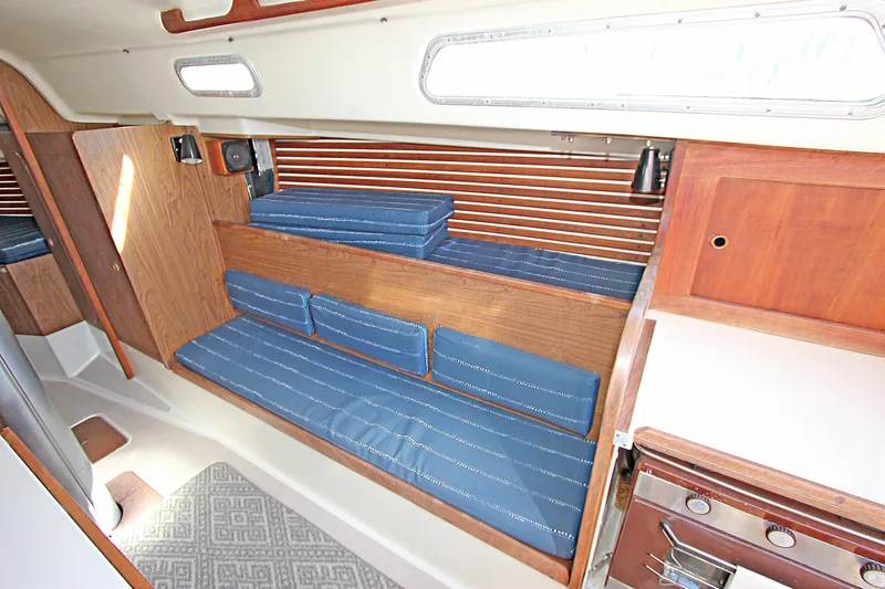 Slide: The Image of Interior of a 1977 Pearson 10M sailboat with blue cushioned seating and wooden accents. - 6