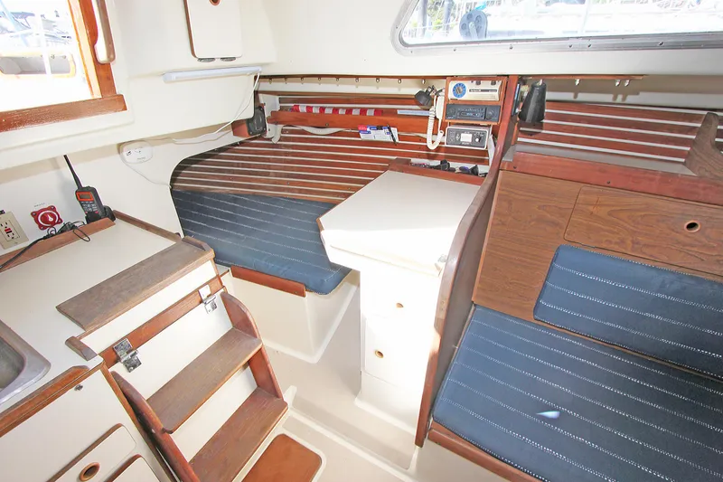 Slide: The Image of 1977 Pearson 10M sailboat interior with wooden accents and blue cushioned seating. - 7