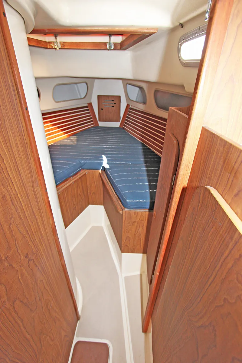 Slide: The Image of 1977 Pearson 10M sailboat interior with wood paneling and blue cushioned seating. - 9
