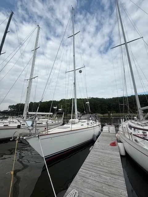 Slide: The Image of 1987 Tartan 40CB sailboat docked at marina, surrounded by other boats, under cloudy sky. - 11