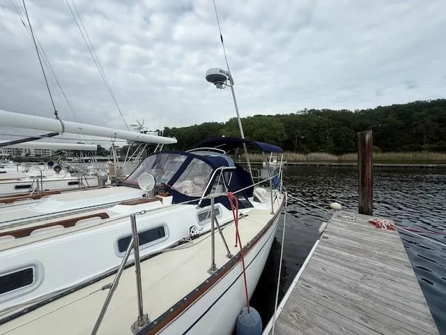 Slide: The Image of 1987 Tartan 40CB sailboat docked at marina, overcast sky, forested background. - 12