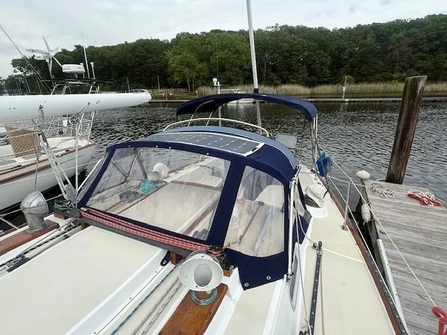 Slide: The Image of 1987 Tartan 40CB sailboat docked, featuring blue canopy and wooded surroundings. - 15