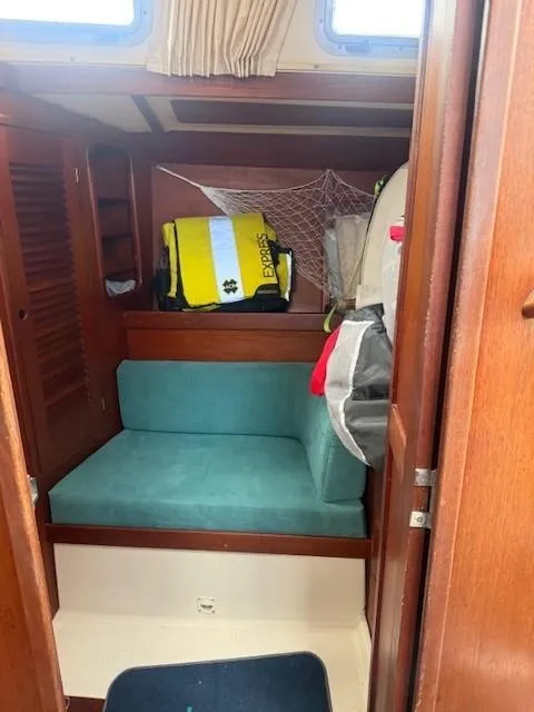 Slide: The Image of 1987 Tartan 40CB cabin interior with teal seating and storage area. - 19