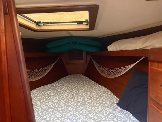Slide: The Image of Cozy cabin interior of 1987 Tartan 40CB sailboat with patterned bedding and storage nets. - 20