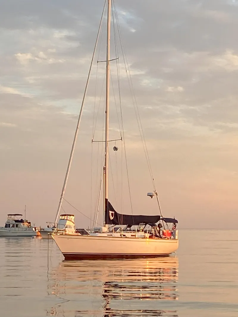 Slide: The Image of 1987 Tartan 40CB sailboat on calm water at sunset, with other boats in the background. - 49