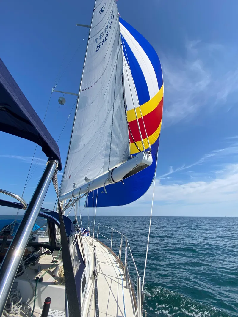 Slide: The Image of 1987 Tartan 40CB sailboat with colorful spinnaker sailing on open sea under clear blue sky. - 6