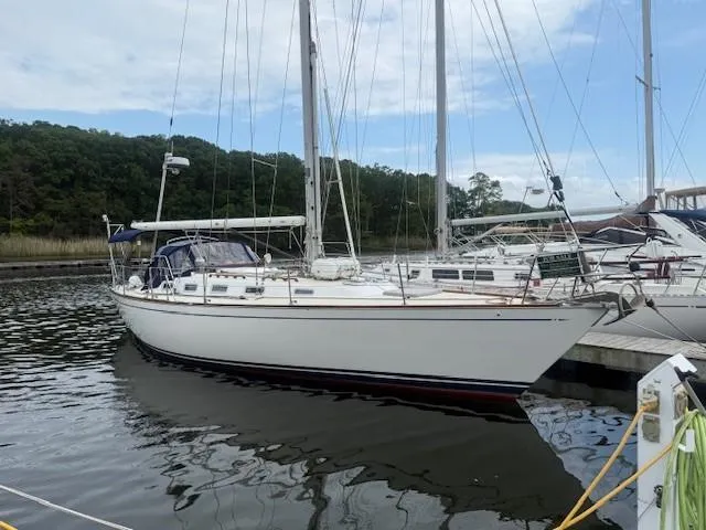 Slide: The Image of 1987 Tartan 40CB sailboat docked in a marina, surrounded by calm water and trees. - 8