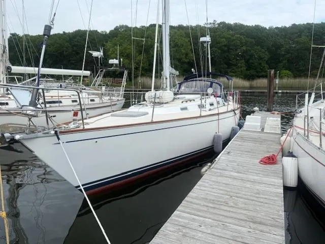 Slide: The Image of 1987 Tartan 40CB sailboat docked at a marina with lush green trees in the background. - 9