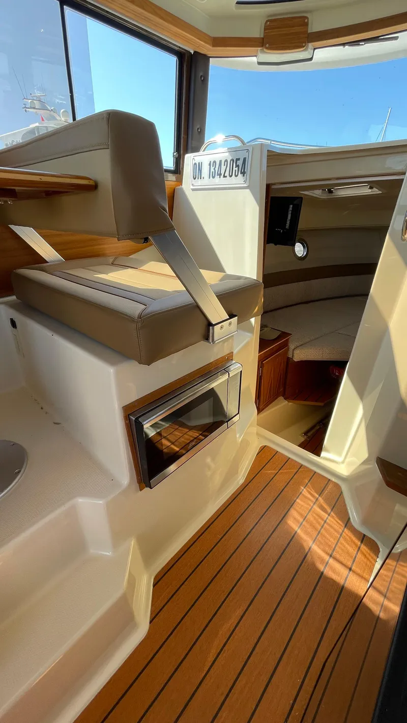 Slide: The Image of 2022 Ranger Tugs R-25 interior with wood flooring and seating area. - 16