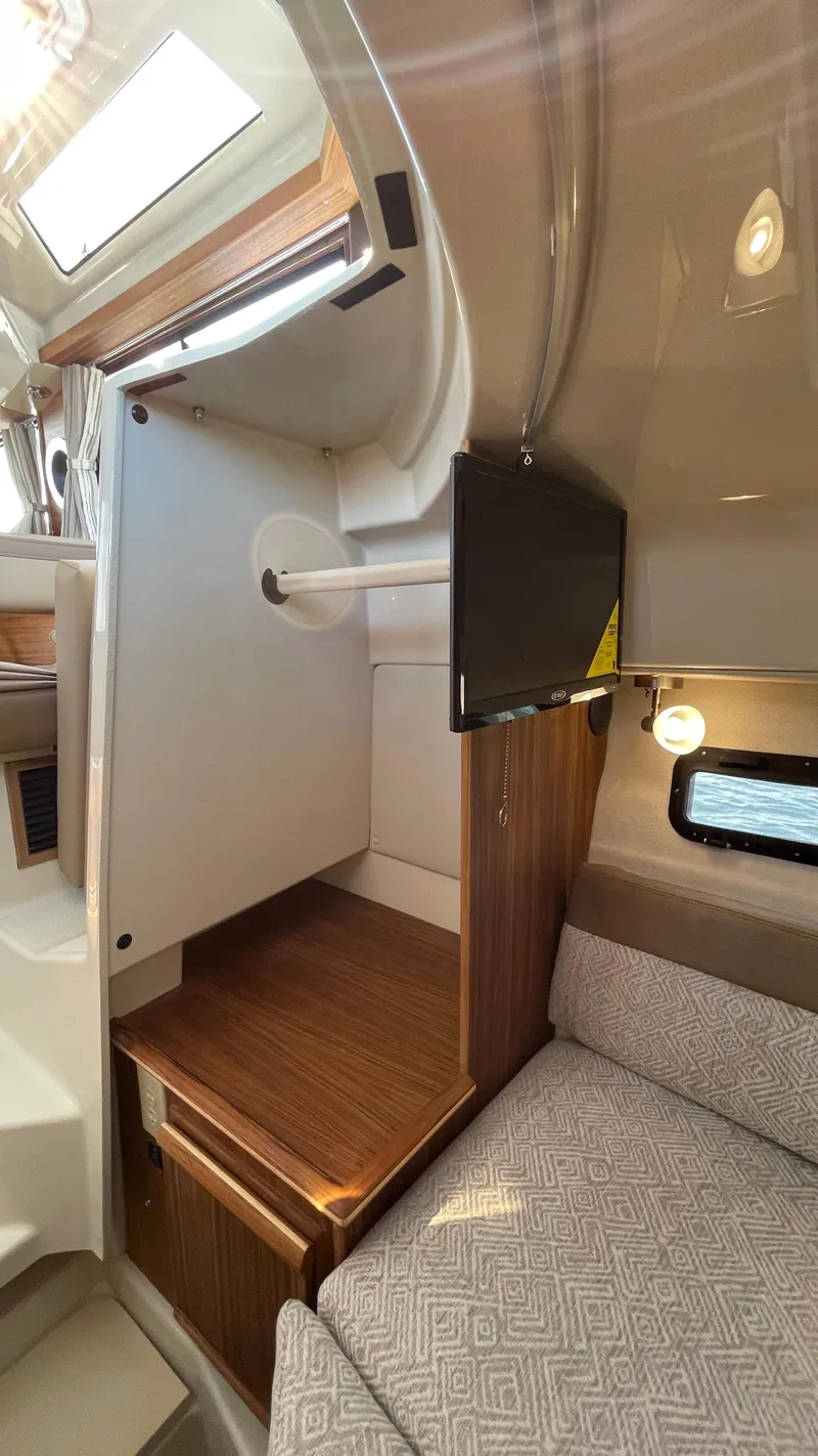 Slide: The Image of 2022 Ranger Tugs R-25 interior with wood accents and a mounted TV. - 21