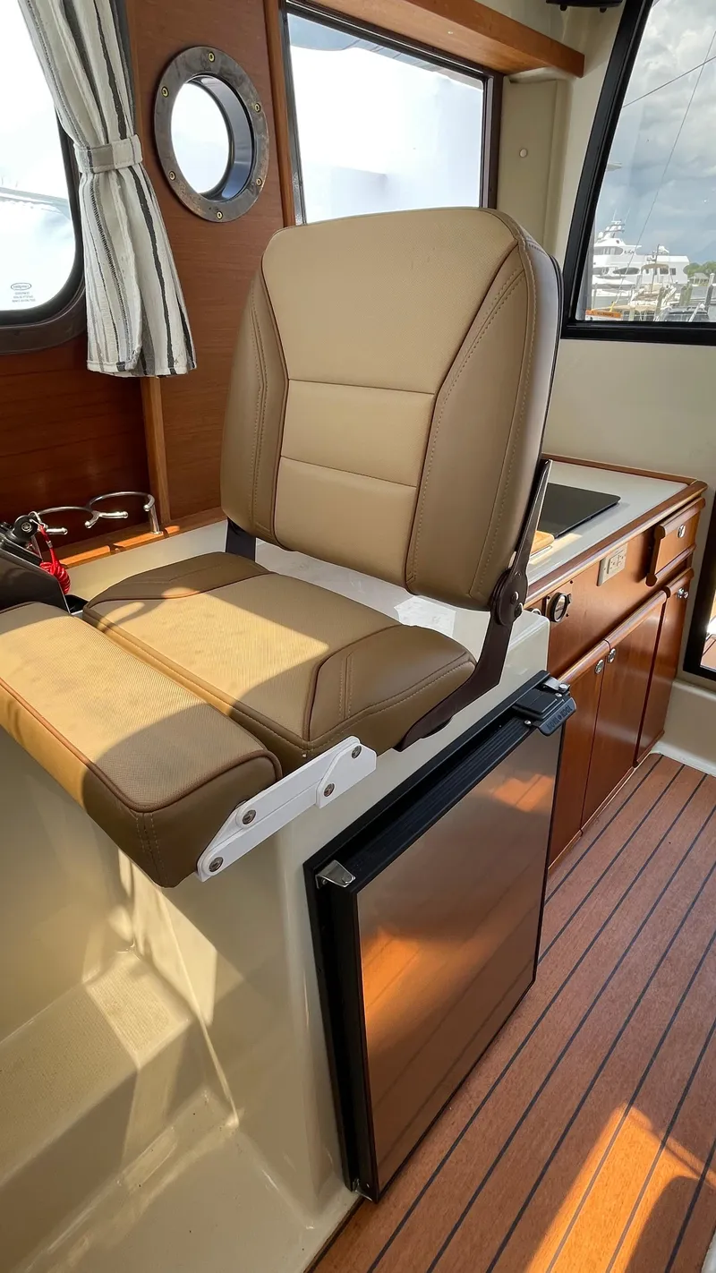 Slide: The Image of 2022 Ranger Tugs R-25 interior with tan seating and wooden cabinetry. - 25