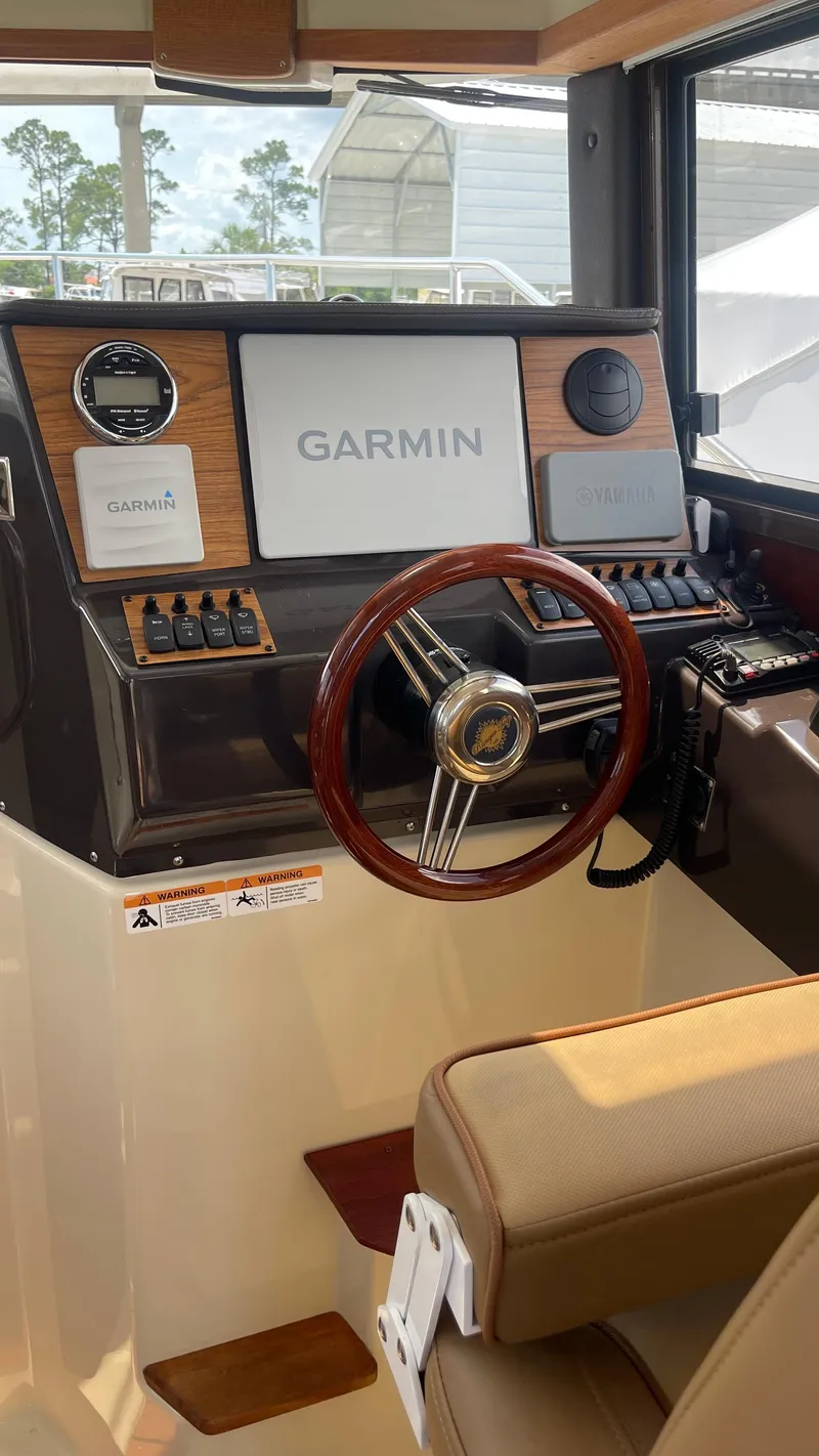 Slide: The Image of 2022 Ranger Tugs R-25 helm with Garmin navigation system and wood-accented steering wheel. - 26