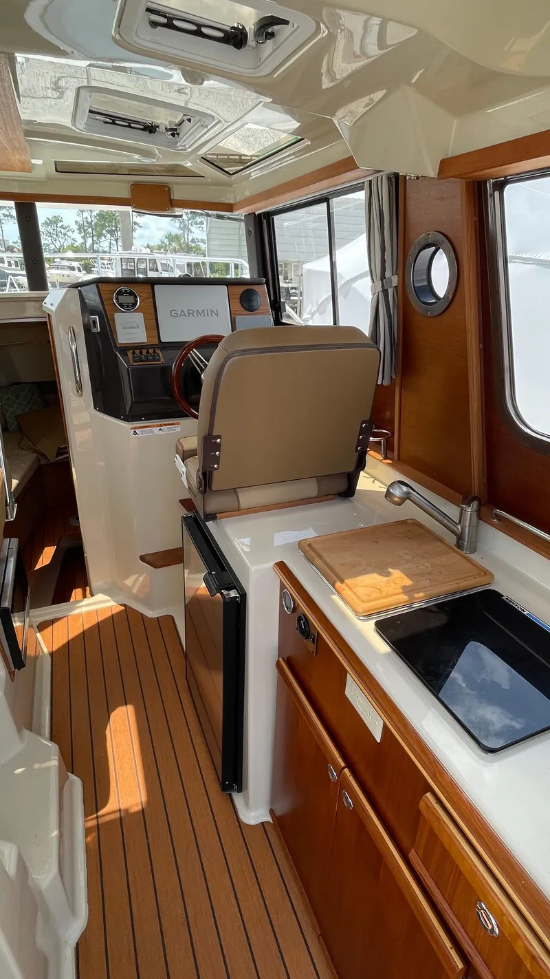 Slide: The Image of Interior of 2022 Ranger Tugs R-25 boat with helm, kitchenette, and wood accents. - 31