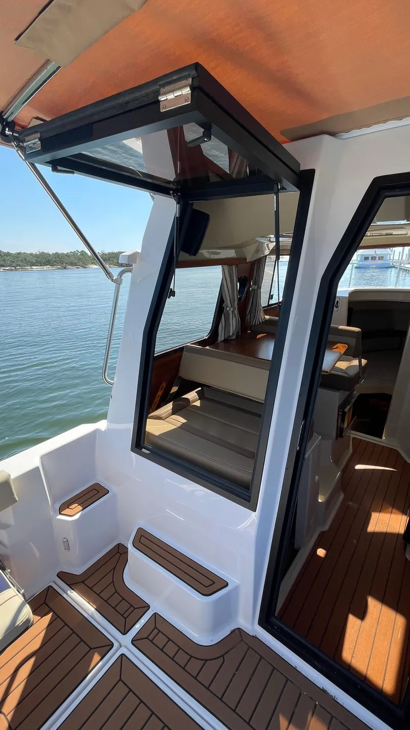 Slide: The Image of 2022 Ranger Tugs R-25 boat interior with open door and wooden flooring. - 9