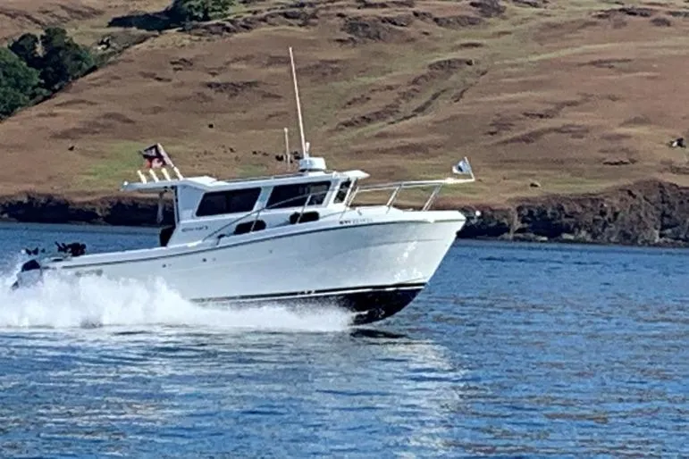 The Image of 2014 Ocean Sport Legacy #4 boat cruising on a scenic waterway. - 0