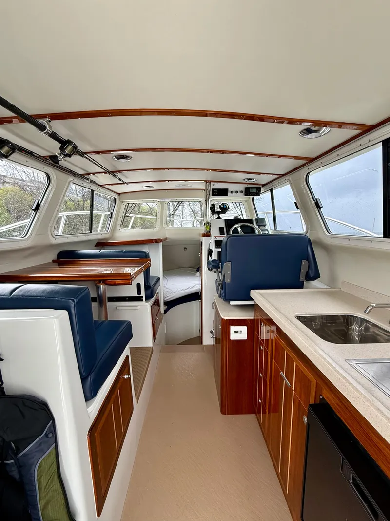 Slide: The Image of Interior of 2014 Ocean Sport Legacy #4 boat with seating, kitchenette, and helm. - 10