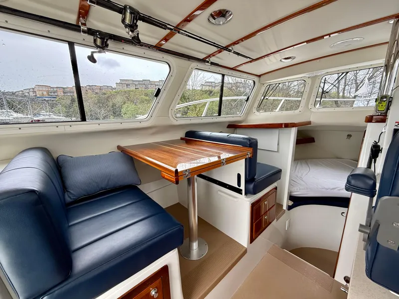 Slide: The Image of Interior of 2014 Ocean Sport Legacy #4 boat with blue seating and wooden table. - 13